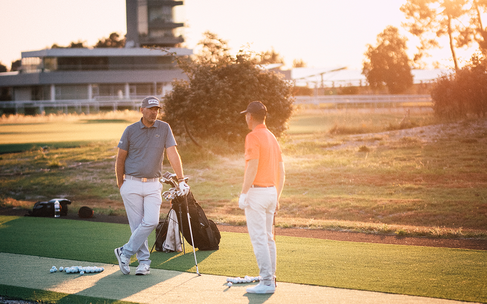 Deux hommes discutent sur un terrain de golf.