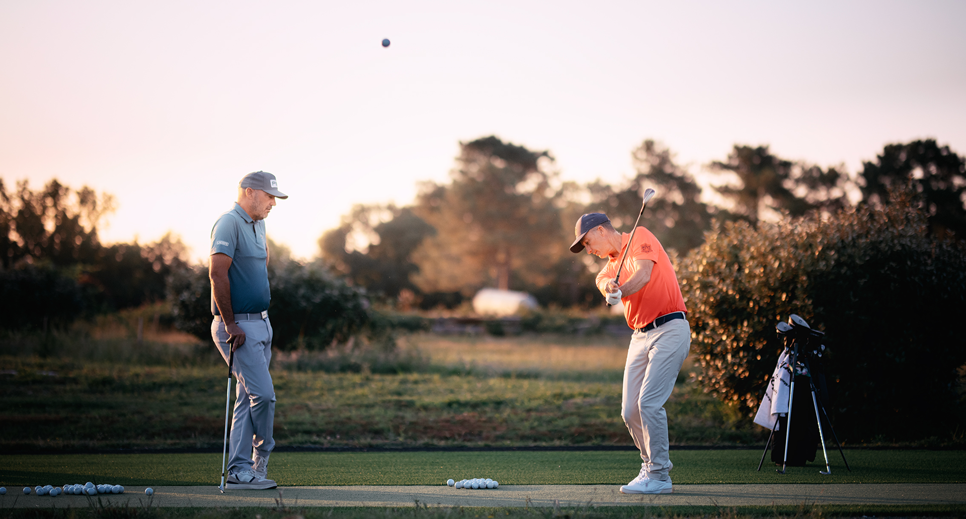 Un homme fait un swing, un autre homme le regarde.